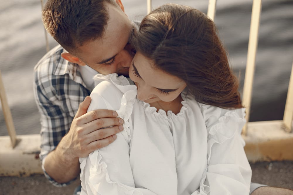 A husband tenderly embracing his wife, his face resting against her hair.