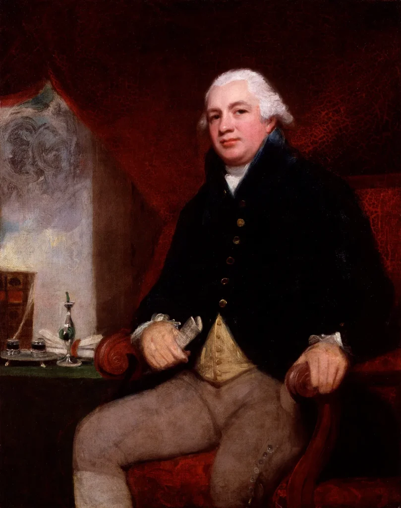 Oil painting by George Romney of Robert Raikes seated in a dark coat, white wig and buff breeches beside a window, held in the National Portrait Gallery, London.